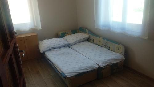 1 dormitorio pequeño con 2 camas individuales y 2 ventanas en Maria Andrea House, en Balatonkeresztúr
