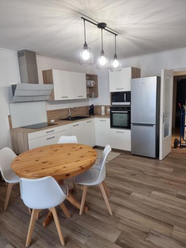 - une cuisine avec une table en bois et des chaises blanches dans l'établissement Superbe 3 pièces épurée de 65 m2, refait à Neuf, dans residence calme, climatisé, place de parking privée, à 800 m de la plage, à Antibes
