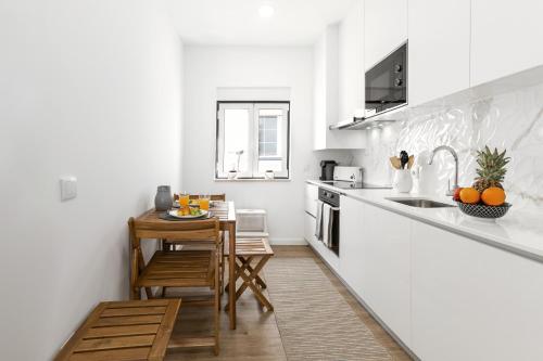 a white kitchen with a small table and a counter at Seaside Salty Escape in Nazaré