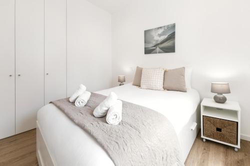 a white bedroom with two beds with towels at Seaside Salty Escape in Nazaré