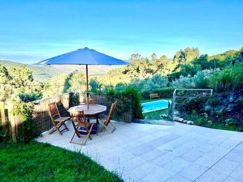 a patio with an umbrella and a table and chairs at Casa Amarela - Mondim de Basto in Mondim de Basto