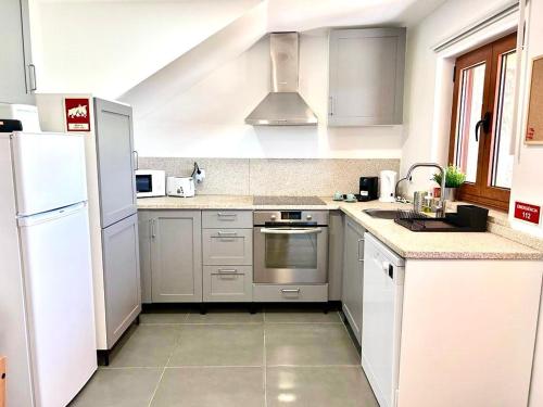 a kitchen with white cabinets and a stove top oven at Casa Amarela - Mondim de Basto in Mondim de Basto