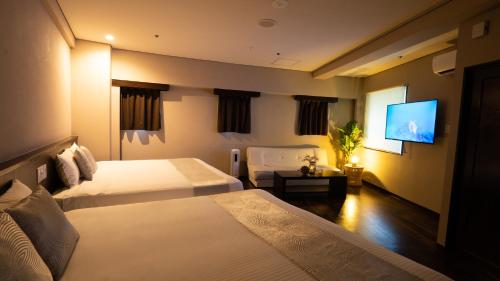 a hotel room with two beds and a flat screen tv at Rycom Crystal Hotel in Okinawa City