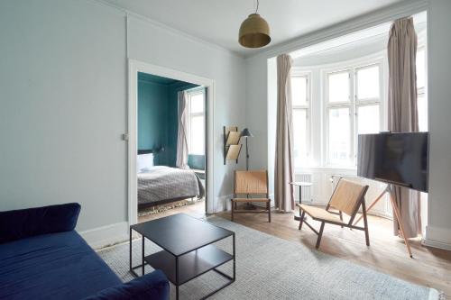 un salon avec un canapé bleu et une chambre dans l'établissement Perfect for Friends & Families 2 Bedroom Apartment in CPH, à Copenhague