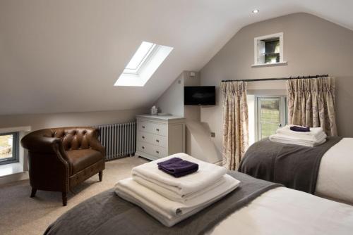 een slaapkamer met 2 bedden, een stoel en een raam bij The Granary at Rothley East Shield in Longwitton