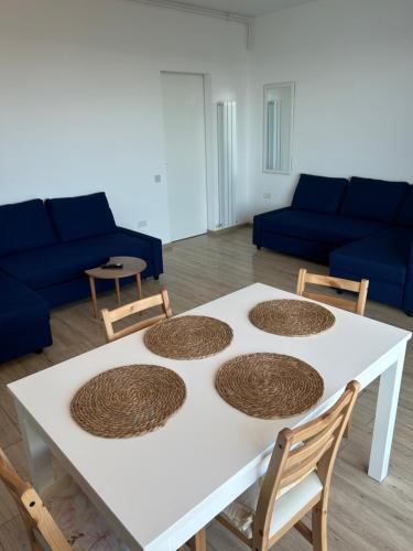 a white table with four chairs and a blue couch at Anda2 in Mamaia