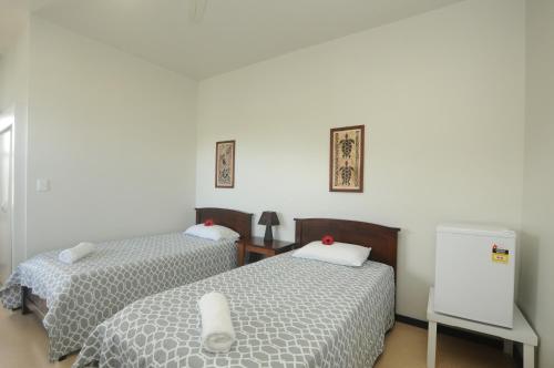 a bedroom with two beds and a white wall at Talofa Inn in Apia