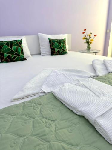 a white bed with green and white sheets and pillows at 2 Комнатные апартаменты ЖК JAIYK RIVERSIDE на берегу Урала in Atyraū