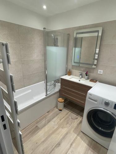 une salle de bain avec une machine à laver et un lave-linge dans l'établissement Superbe 3 pièces épurée de 65 m2, refait à Neuf, dans residence calme, climatisé, place de parking privée, à 800 m de la plage, à Antibes
