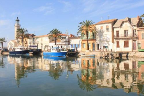 un groupe de bateaux dans un canal avec des bâtiments dans l'établissement Maison à 800m des Remparts, à Aigues-Mortes