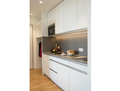 a kitchen with white cabinets and a counter top at Seven Hotel + Boardinghouse in Herzogenaurach