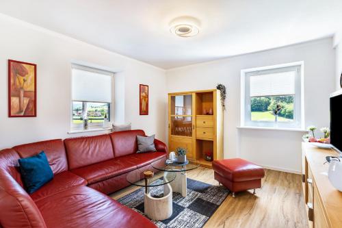 sala de estar con sofá de cuero rojo en Ferienwohnung Geisbergblick en Seelbach