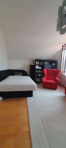 a bedroom with a bed and a red chair at Orsolya apartman in Nyíregyháza