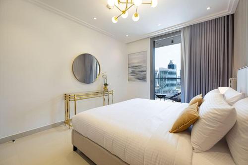 a white bedroom with a large bed and a window at Cozy 1Bed Connected to DubaiMall BurjKhalifa 5min in Dubai