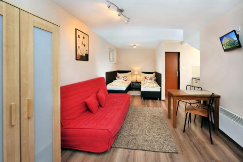 a living room with a red couch and a table at APLEND Villas Tatry Holiday in Veľký Slavkov