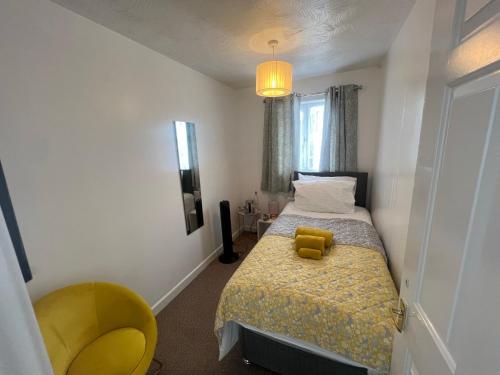 a bedroom with a bed with a yellow teddy bear on it at Corby Guest House in Corby