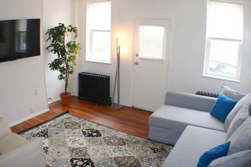 a living room with a couch and a plant at Urban Oasis - 3BR 2BA - City View- Private Parking in Pittsburgh