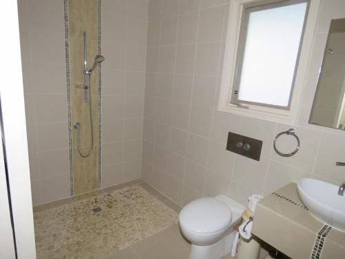 a bathroom with a shower and a toilet and a sink at 5 Little Penguin Crt, Cowes in Cowes
