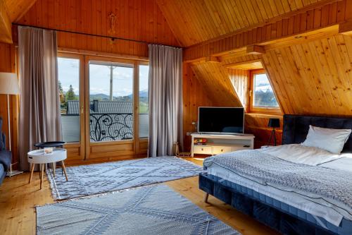 - une chambre avec un lit, une télévision et une fenêtre dans l'établissement DOMKI Sielsko Góra, à Gliczarów