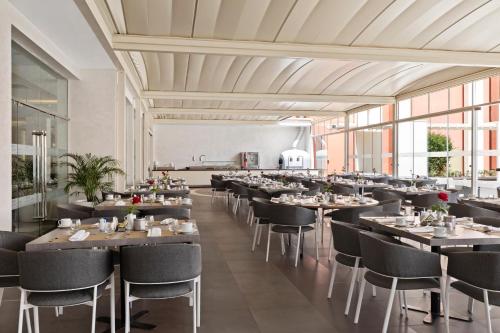 a dining room with tables and chairs and windows at Savoy Le Grand Hotel Marrakech in Marrakech