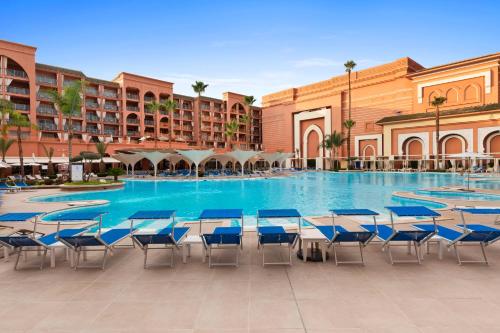 a large swimming pool with tables and chairs in a resort at Savoy Le Grand Hotel Marrakech in Marrakech