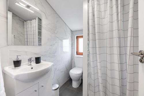 a white bathroom with a sink and a toilet at Casa Amarela - Mondim de Basto in Mondim de Basto