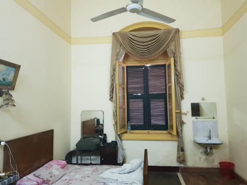 a bedroom with a bed and a window with a fan at Clement's House Hostel in Alexandria
