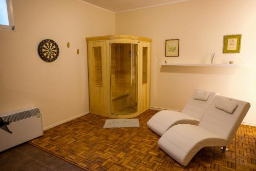 a living room with a white chair and a shower at Villa Monforte Barolo with private pool - LANGHE GATEWAY in Monforte dʼAlba