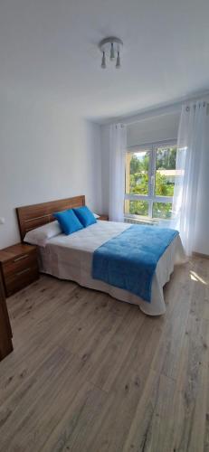 - une chambre avec un lit doté de draps bleus et une fenêtre dans l'établissement Piso al lado de la playa, à Boiro