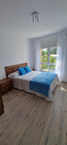 a bedroom with a bed with blue sheets and a window at Piso al lado de la playa in Boiro