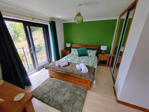 a bedroom with green walls and a bed with two pillows at Bryn Mynach Annex in Barmouth