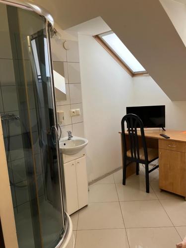 a bathroom with a shower and a sink and a desk at Zajazd Okalina in Opatów