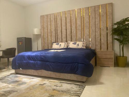 una camera con un letto blu e una grande testiera del letto di التوفيق للوحدات السكنية T1 a Al Ahsa
