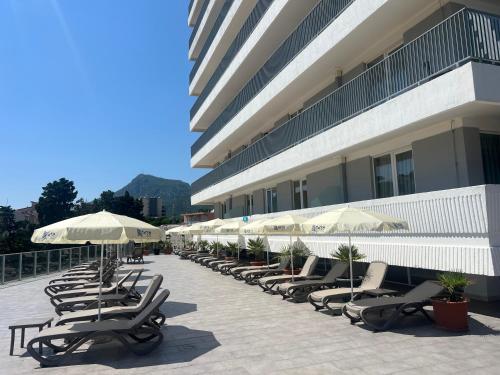 a row of lounge chairs and umbrellas next to a building at Hotel Sato Conference & SPA Resort in Sutomore