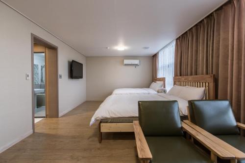 a bedroom with a large bed and two chairs at Elin Hotel in Jeju
