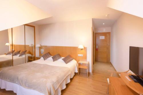 a hotel room with two beds and a flat screen tv at Villa De Llanes in Llanes