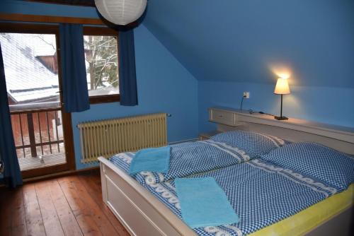 Schlafzimmer mit einem Bett mit blauen Wänden und einem Fenster in der Unterkunft Domek u Bělidla in Krásná Lípa