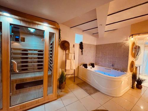 une grande salle de bain avec une baignoire et une grande fenêtre dans l'établissement Magnifique appartement bohème / sauna / balneo, à Valros