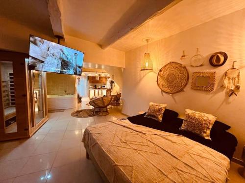 una camera con un grande letto e una TV a schermo piatto di Magnifique appartement bohème / sauna / balneo a Valros