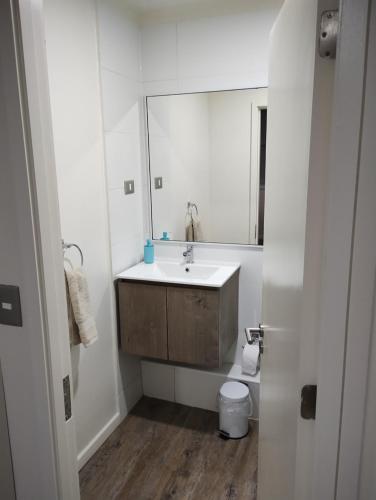 Baño blanco con lavabo y espejo en Departamento pelluco alto II en Puerto Montt