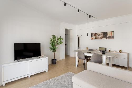 uma sala de estar branca com uma mesa e uma televisão em JOIVY Cosy apt in Parede near the beach em Parede