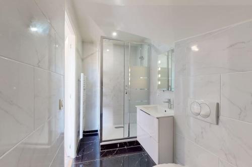 ein weißes Bad mit einer Dusche und einem Waschbecken in der Unterkunft 06.Studio#Creteil#Loft#Cinéma#Exclusif in Créteil