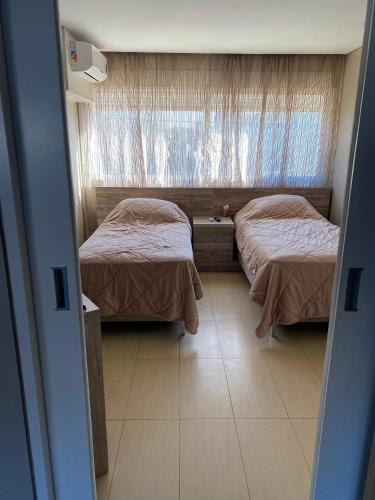 two beds in a small room with a window at Casa Guemes in Mar del Plata