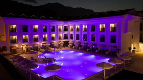 a hotel with a pool and tables and umbrellas at night at Saint Star Kemer - Adult Only in Kemer
