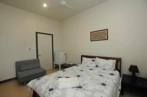 a bedroom with a bed and a chair and a mirror at Talofa Inn in Apia