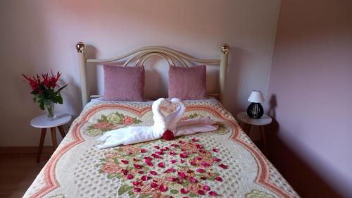 a swan laying on top of a bed with flowers at Chalés Mimar Lumiar Suítes individuais in Lumiar