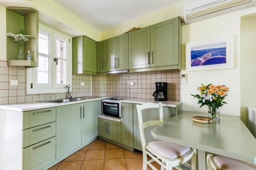 a kitchen with green cabinets and a table at Sentefi Maisonette in Skopelos Town