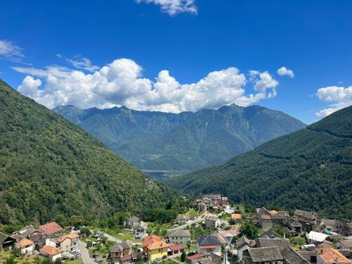 un village dans une vallée avec des montagnes en arrière-plan dans l'établissement CASA DEL CIOS calda e intima casetta immersa nel verde delle montagne, à Alpe Basciumo