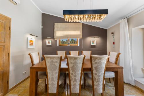 a dining room with a wooden table and chairs at Villa Algarve 4 Ensuite Bedrooms, Private Swimming Pool, Beautiful Gardens with water features and natural Bio Pool in Almancil