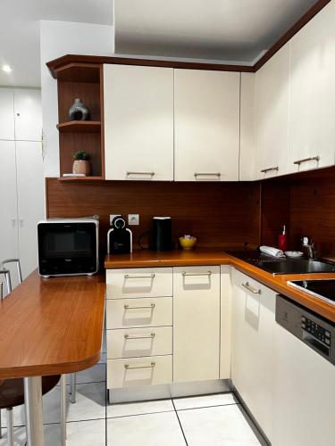 une cuisine avec des armoires blanches et une table en bois dans l'établissement Cannes en plein cœur, à Cannes